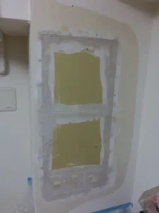 大きく損傷している壁の石膏ボードを補修してパテを掛けた様子