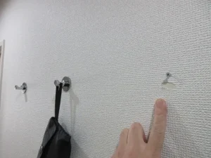 両面テープで壁にフックが取り付けてあり、無理に外して壁紙が剥がれている様子