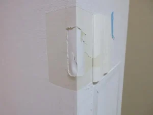 壁紙をめくり、下地のコーナーが破損しているのが分る状態