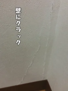 壁にクラック（ひび割れ）が入り、壁紙の裂けや盛り上がりが分かる様子