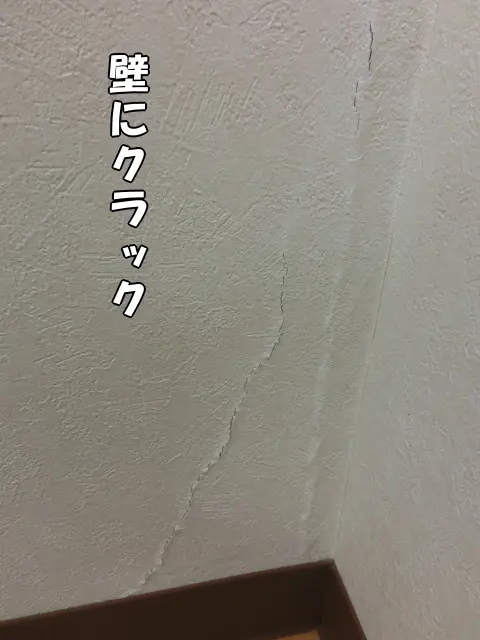 壁にクラック(ひび割れ)が入り、壁紙の裂けや盛り上がりが分かる様子